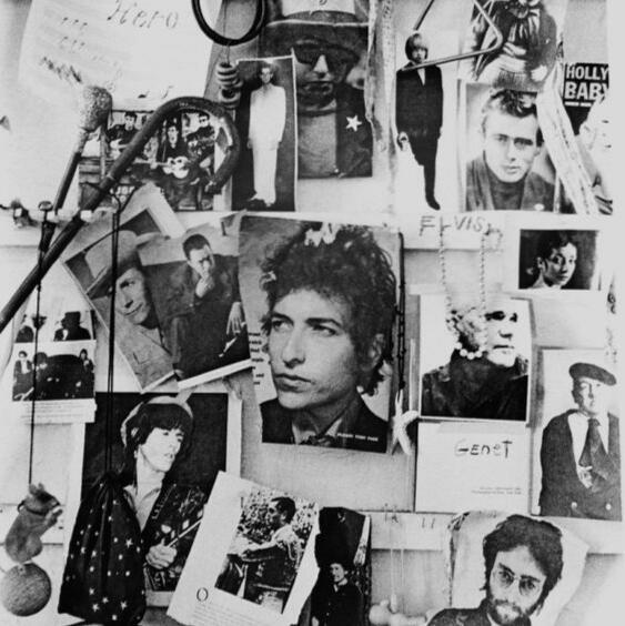 a black and white photo of patti smith's wall in the chelsea hotel, on it are a collection of photos, including hank williams, bob dylan, keith richards, and john lennon.